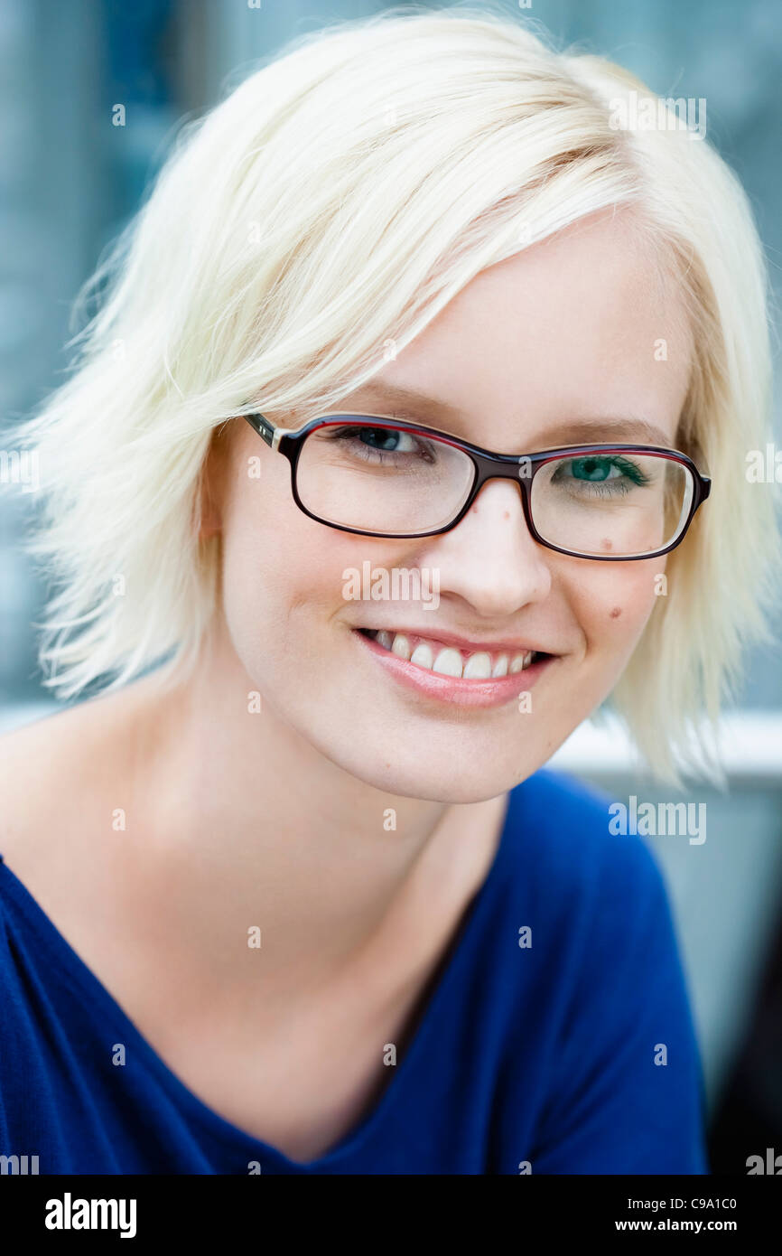 Germany, Bavaria, Munich, Young woman with spectacles, portrait, smiling Stock Photo