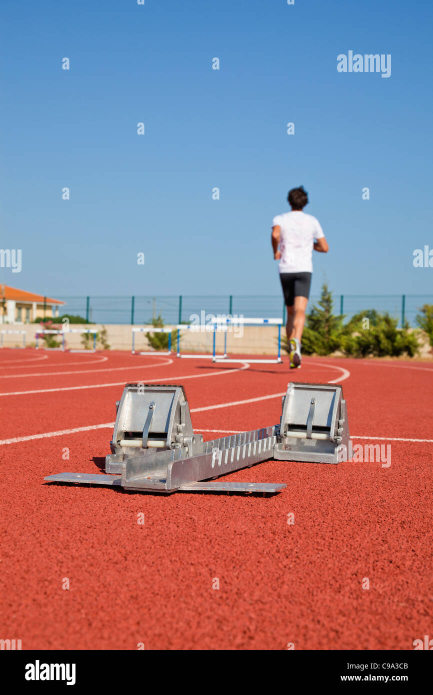 Close-up image of a starting blocks and an athlete running on the track ...