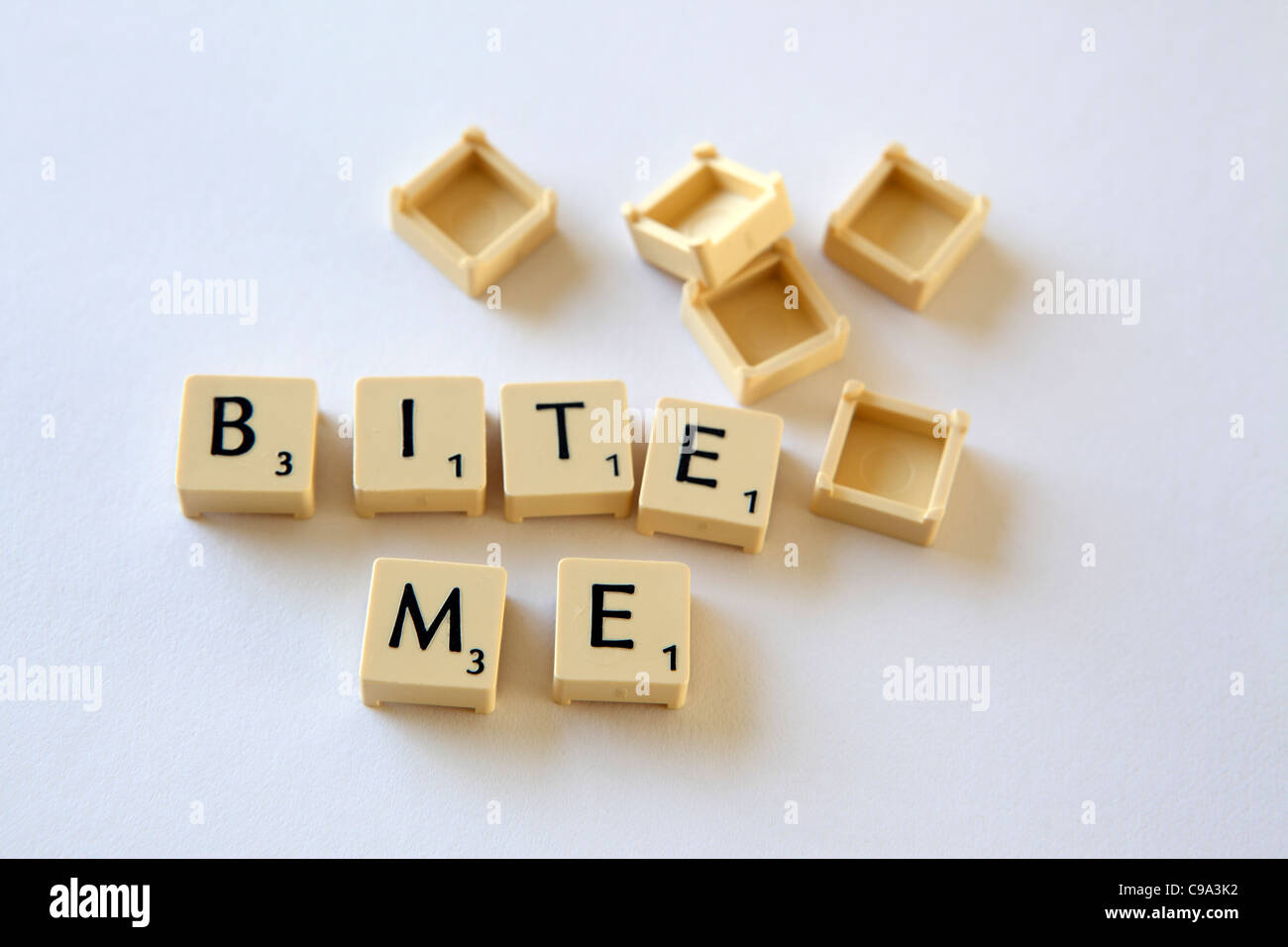 Scrabble tiles / squares spell out 'BITE ME' slogan, white background studio photograph Stock Photo