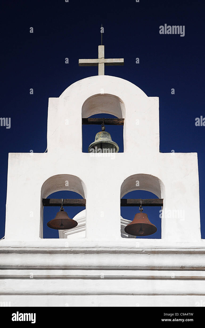 USA, Arizona, Tucson, Mission Church of San Xavier del Bac bells in white bell tower topped with cross. Stock Photo
