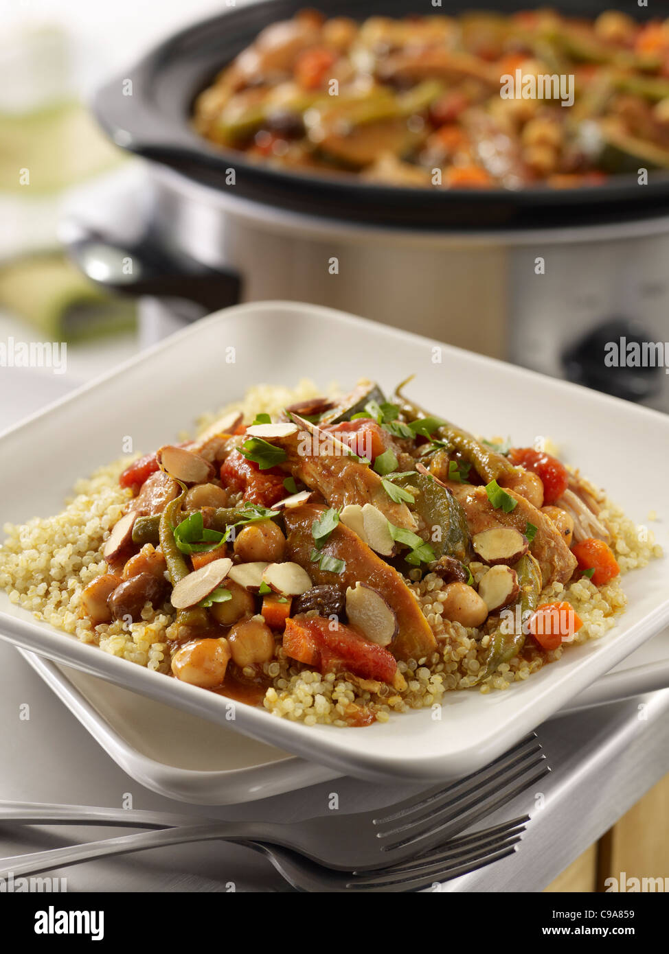 Moroccan chicken stew served over grains in a kitchen setting with a crock pot in the background Stock Photo