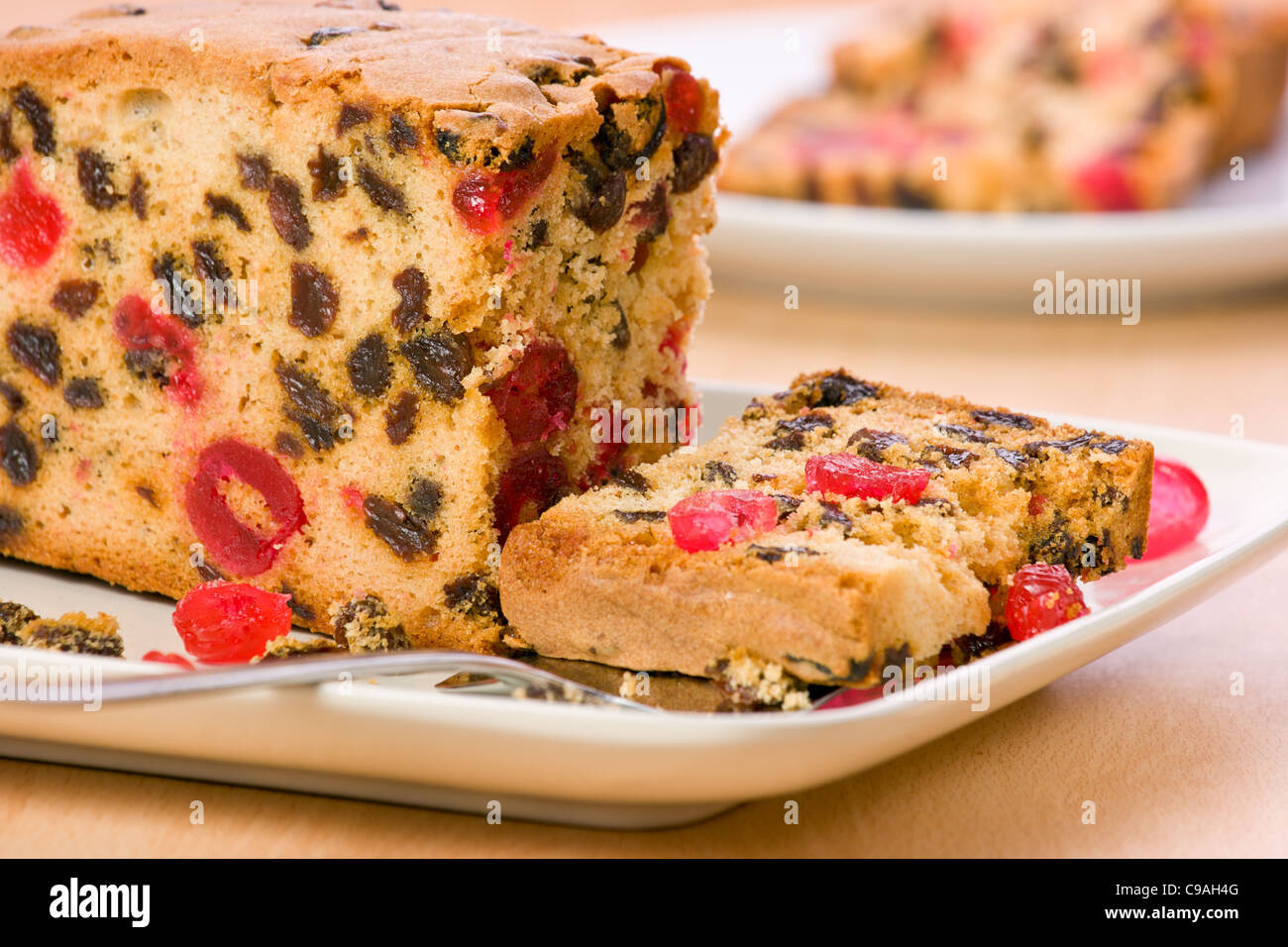 Fruitcake with a slice on cake knife and on a plate slice cut and in the background crumbs scattered on plate Stock Photo