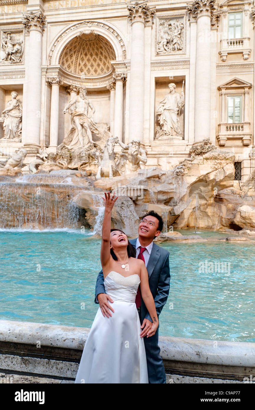 Newlyweds throwing a coin in Fontana di Trevi Stock Photo