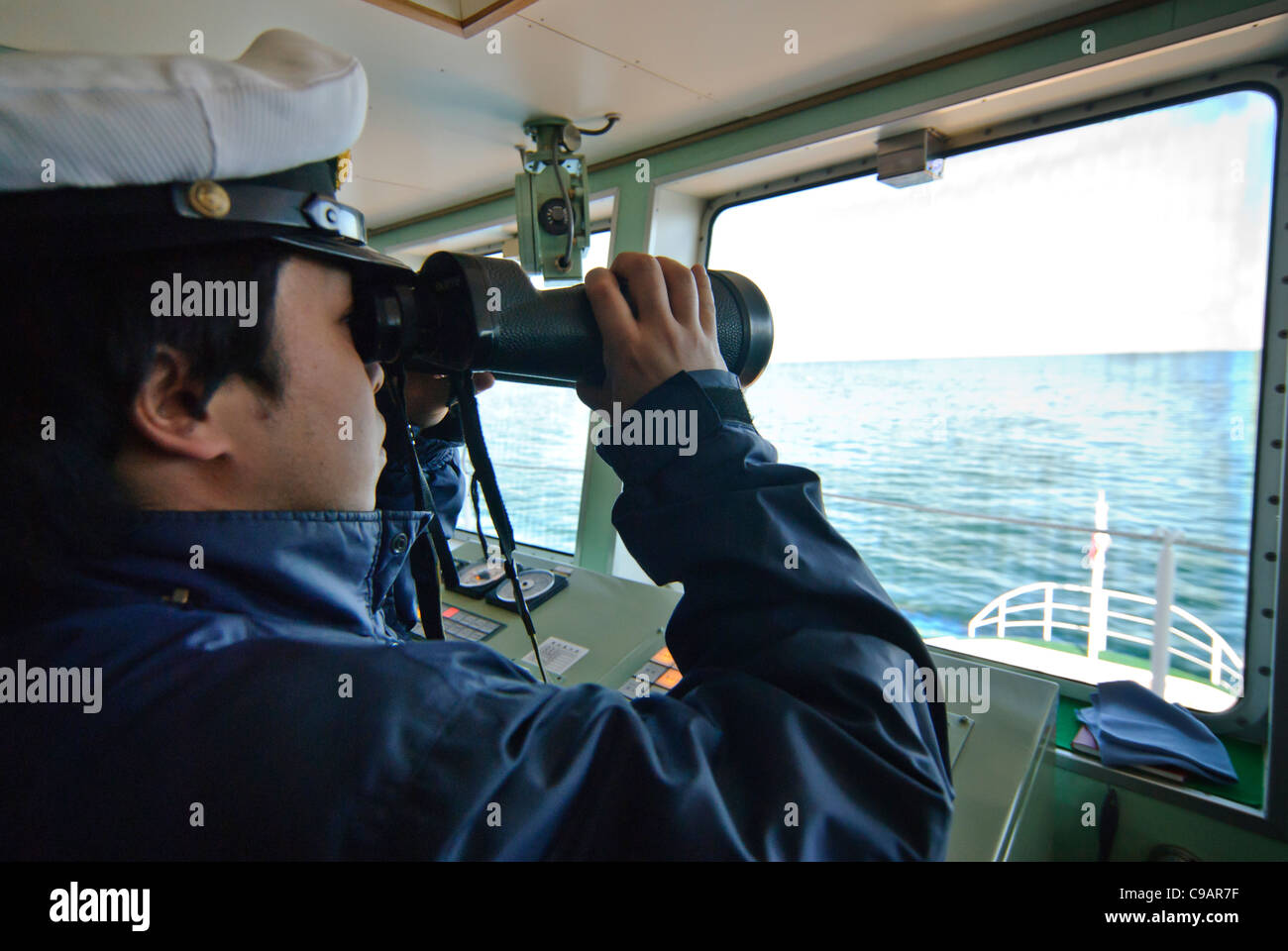 Crew member on board boat, looking through binoculars, Shiretoko and Nemuro, Hokkaido, Japan Stock Photo