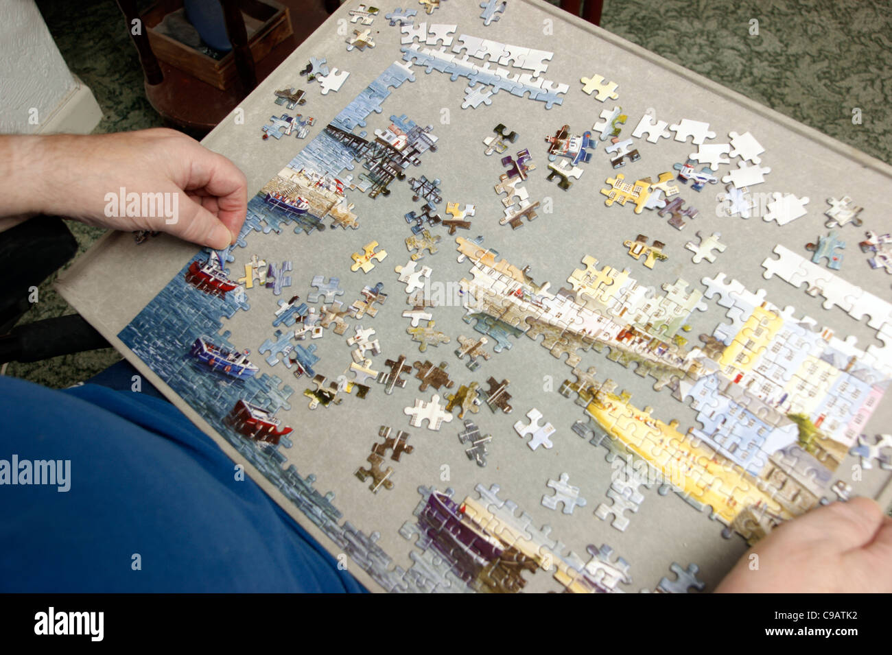Disabled elderly man in a wheelchair doing a jigsaw puzzle to keep his