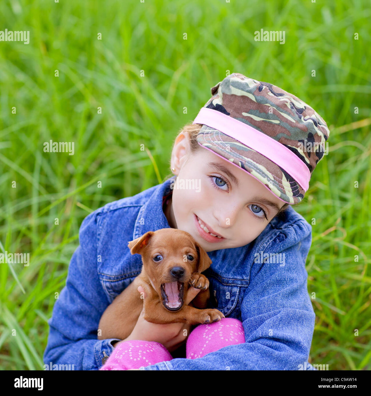little girl with pet puppy mascot mini pinscher in outdoor green grass ...