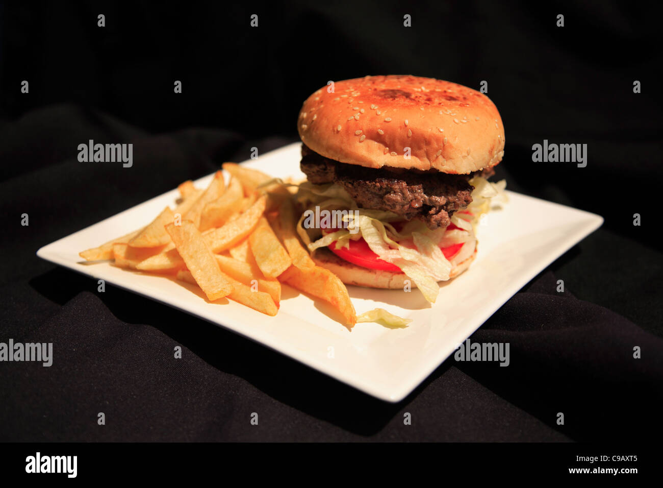 Juicy beef burger with fries on a white plate shot with a shallow depth of field Stock Photo