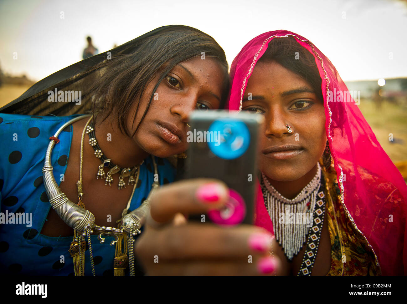 Anita Devi, 13, right and Subita Devi, 13 take a photo with their mobile phone at the world's largest annual cattle fair in the Stock Photo