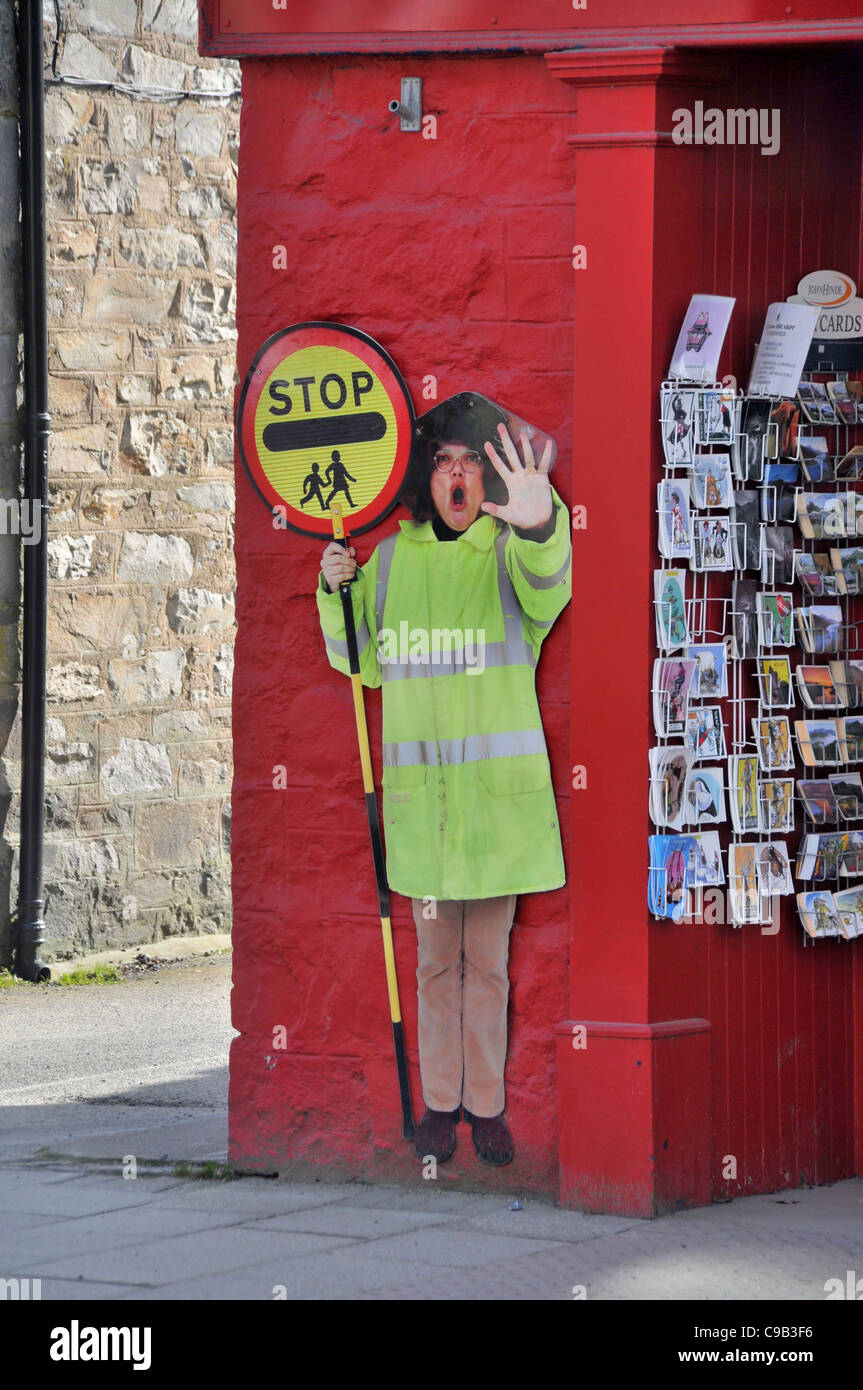 A life size picture of a lollipop lady  stuck on a shop wall on a high street in the  town of Pitlochry. Stock Photo