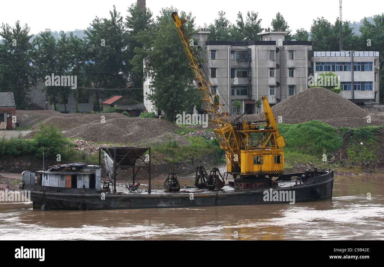 Clamshell dredge crane on the Yangtze River below Jingzhou, China (a welder is working inside the bucket next to the motorcycle) Stock Photo