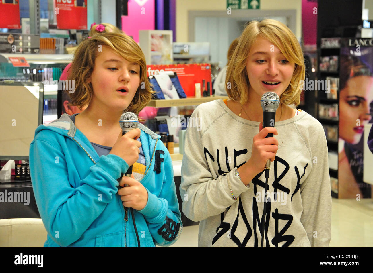 Teenage girls singing karaoke in Boots store at Christmas, Kingston upon Thames, Greater London, England, United Kingdo Stock Photo
