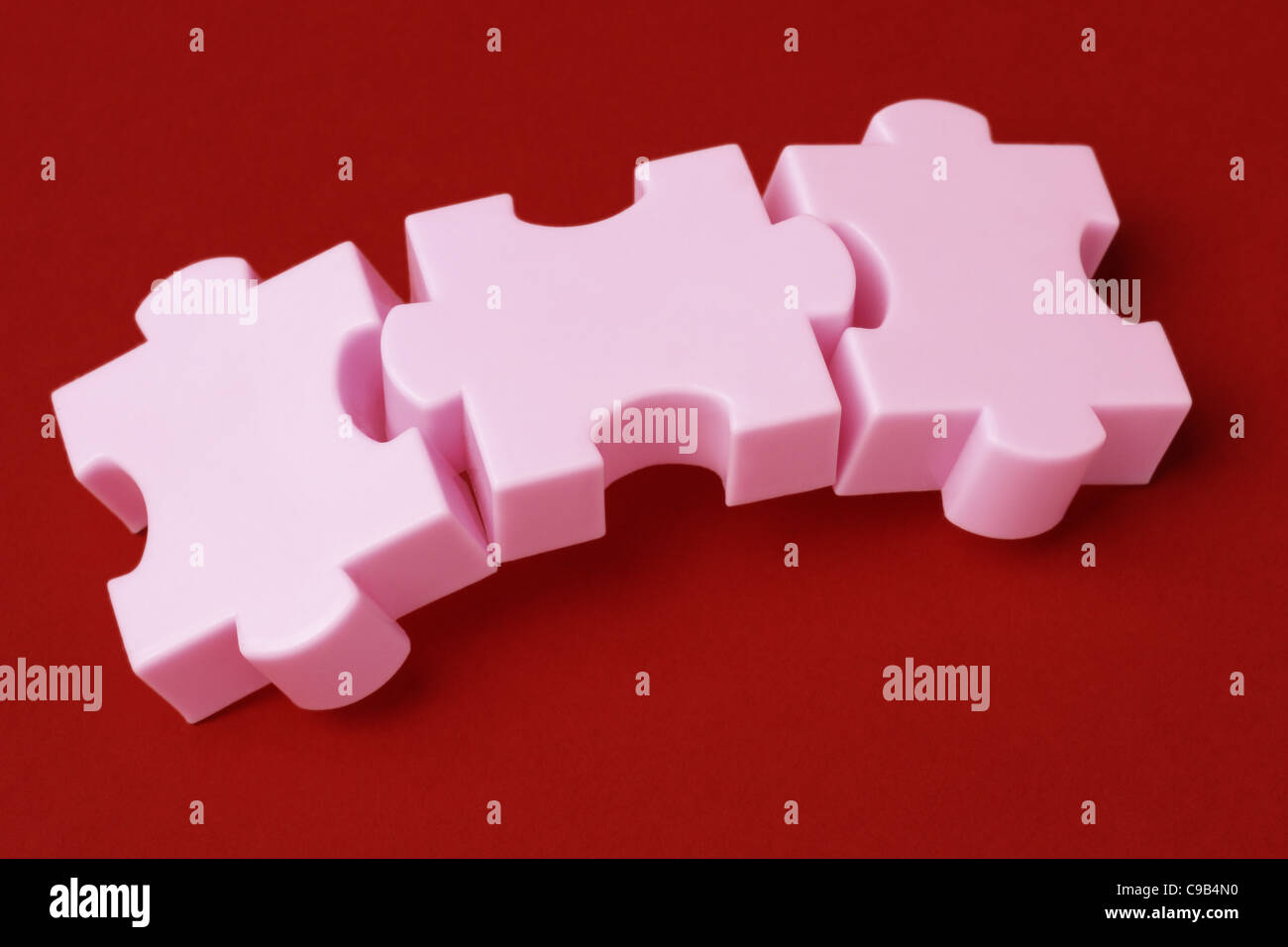 Three interlocking jigsaw puzzle blocks on red background Stock Photo