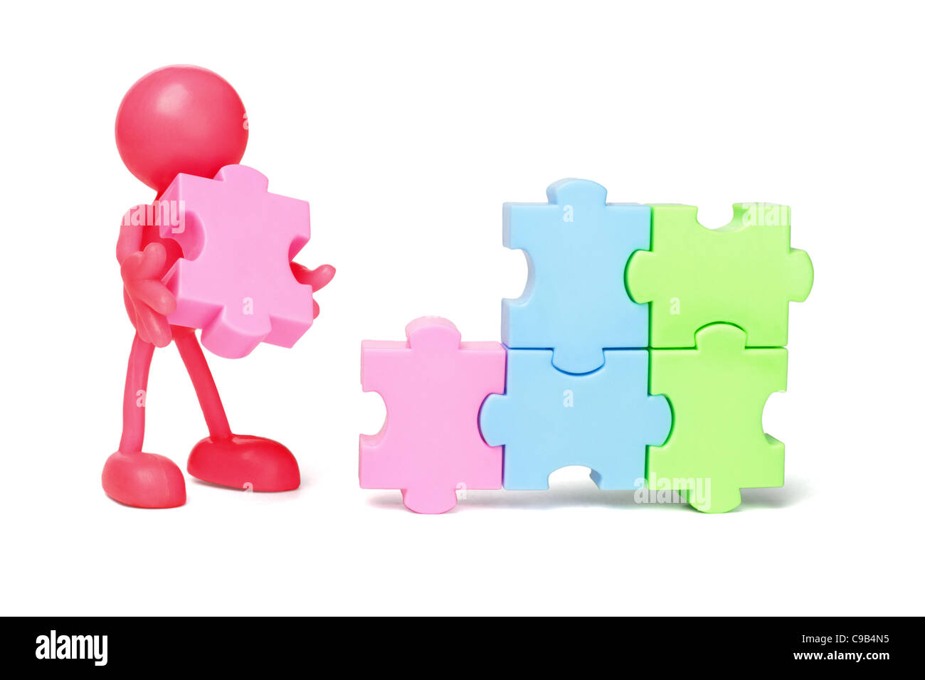 Red faceless figurine working on jigsaw puzzles Stock Photo