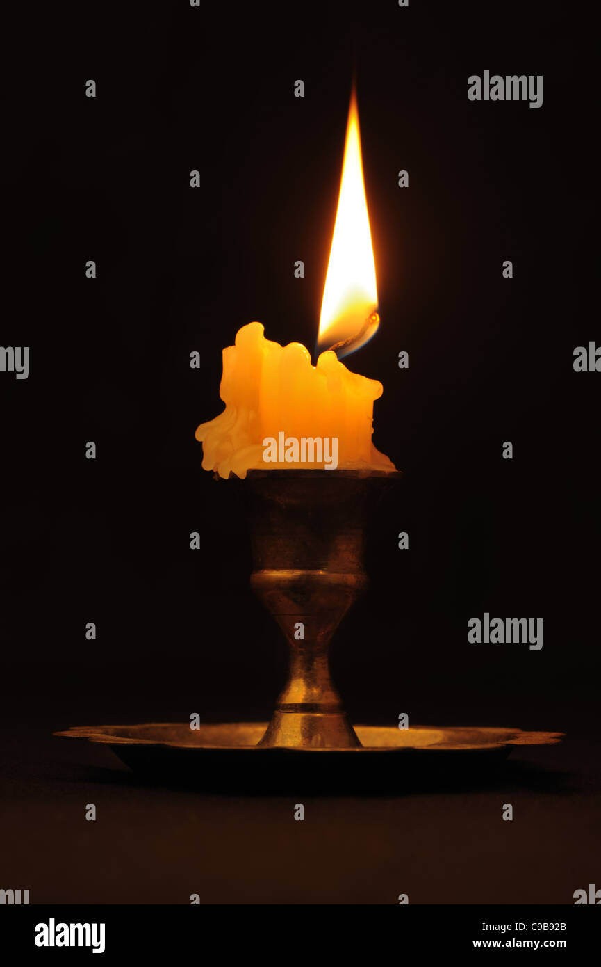 Burning candle. An ancient candlestick, a dark background Stock Photo