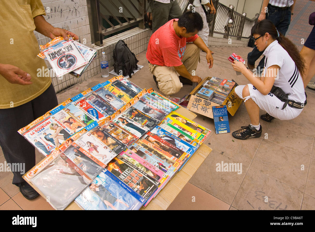 GUANGZHOU, GUANGDONG PROVINCE, CHINA - Street vendor selling pirate DVDs of current hit movies and television shows, and CDs Stock Photo