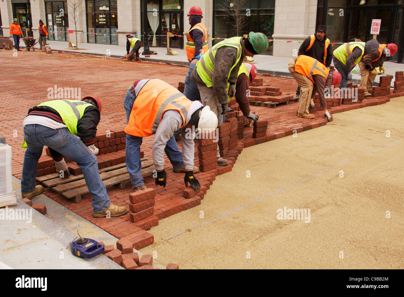 Construction workers lay paving bricks during Marion Street reconstruction project Stock Photo