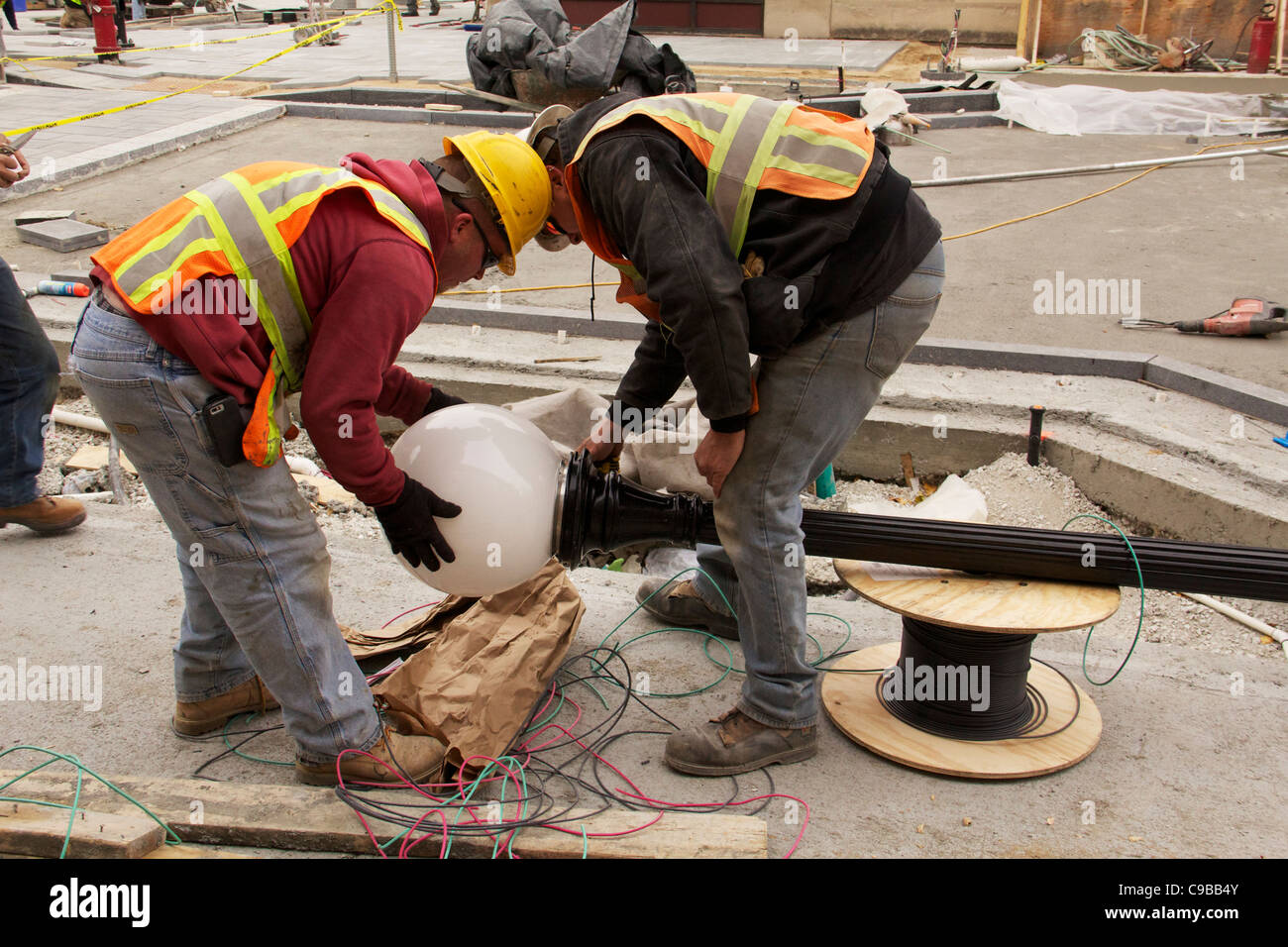 Electricians place diffusion globe on streetlight during Marion Street reconstruction project Stock Photo