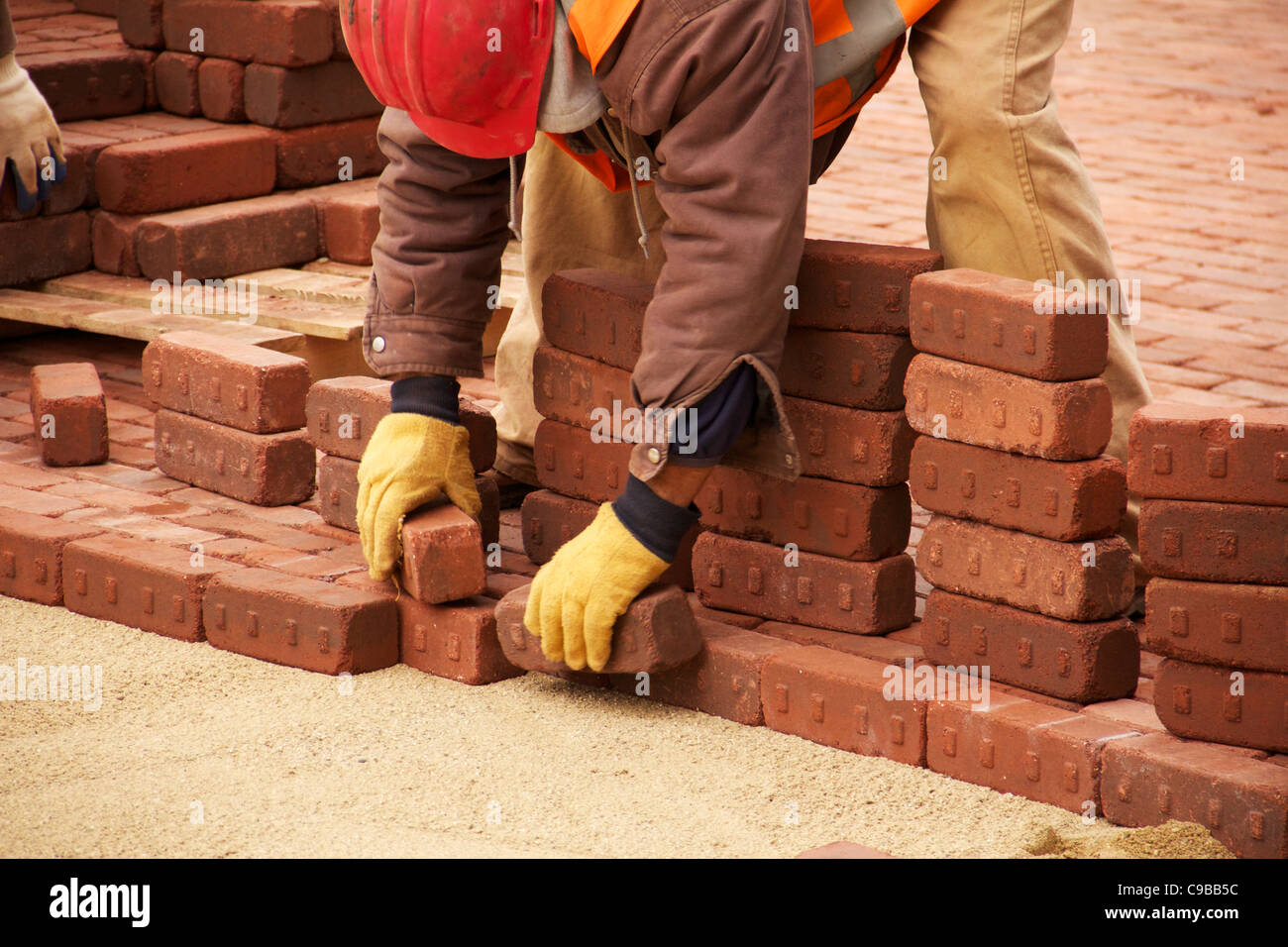 Construction worker lays paving bricks during Marion Street reconstruction project Stock Photo