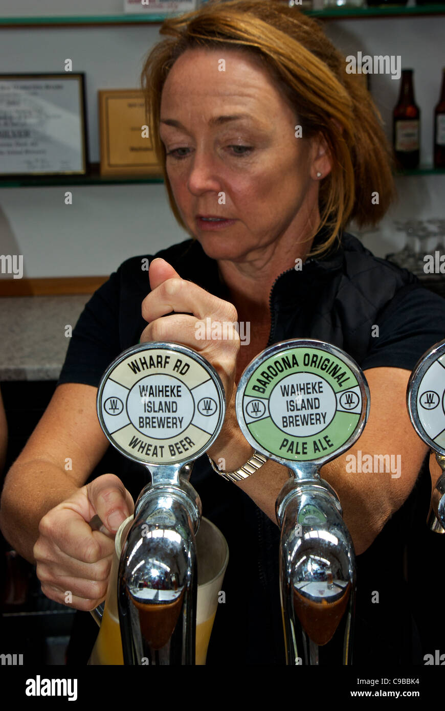 Female pub owner pulling frosty mug of wheat beer on tap at Wild on Waiheke Island microbrewery Stock Photo
