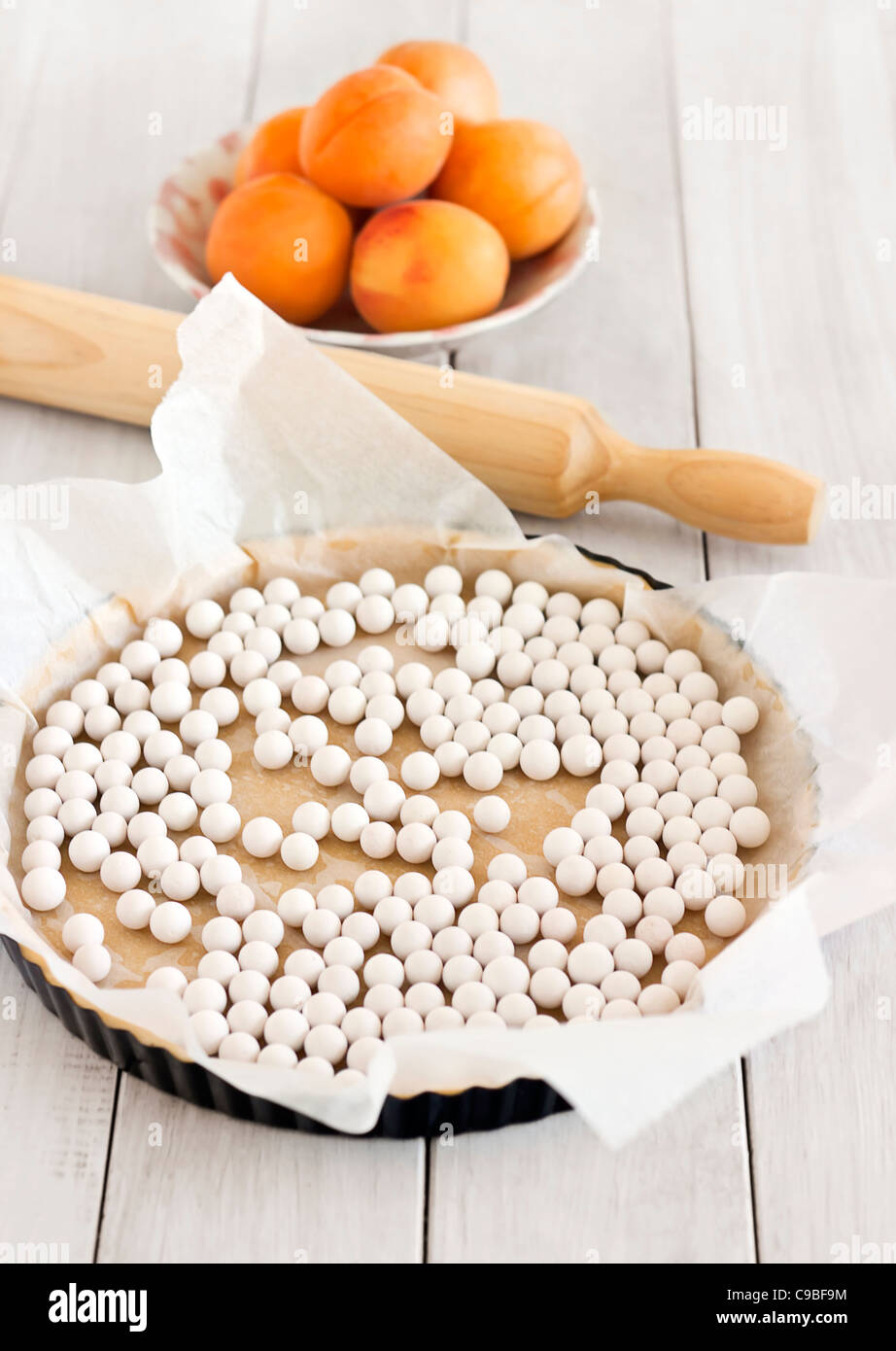 Making an apricot pie rolled dough in a pie tin with weights ready for