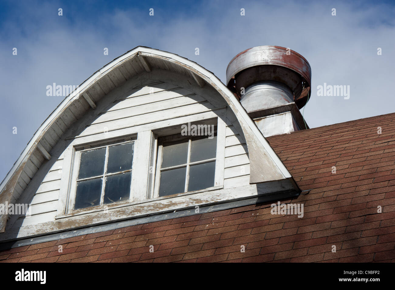 Dormer window on the top of a barn against blue sky Stock Photo