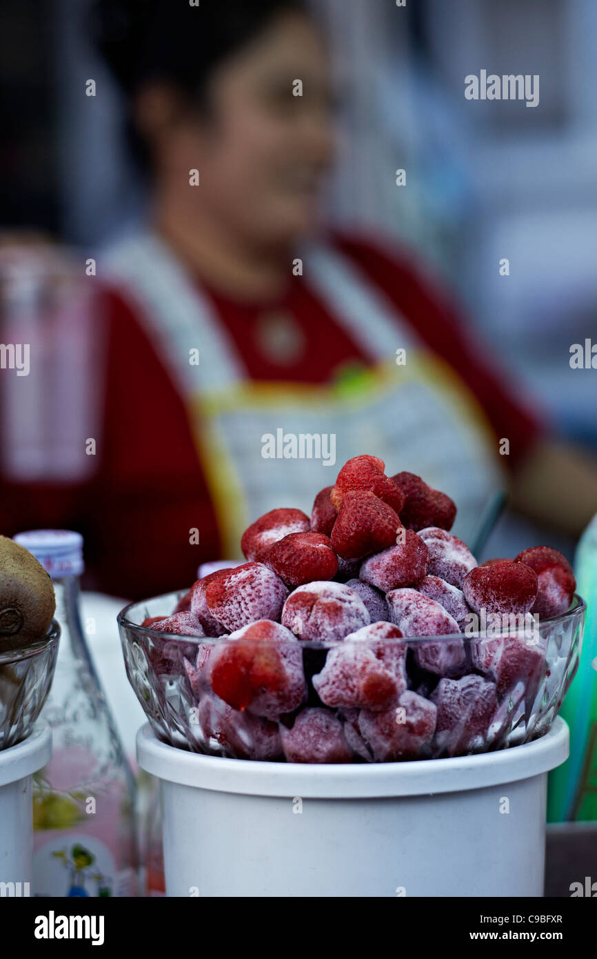 Fresh sugar coated strawberries for sale at a Thailand market stall with out of focus fruit seller in the background. S. E. Asia Stock Photo