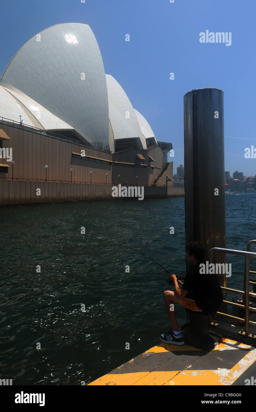 Boy fishing next to Sydney Opera House, Sydney Harbour, NSW, Australia. No MR or PR Stock Photo