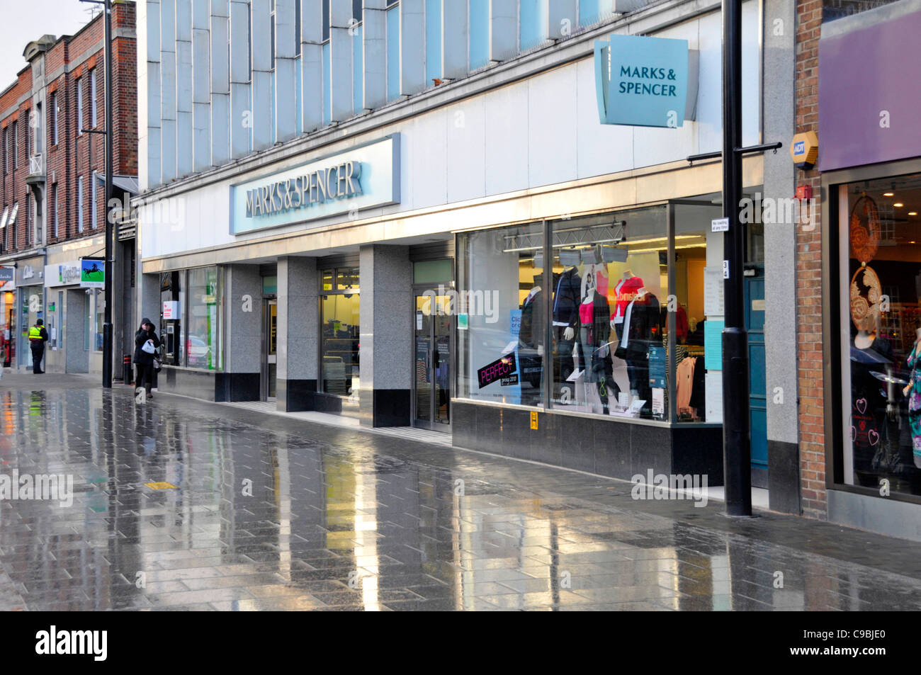 Marks & Spencer shopping High Street store shop window pavement reflections on a rainy January winters day Essex England UK Stock Photo