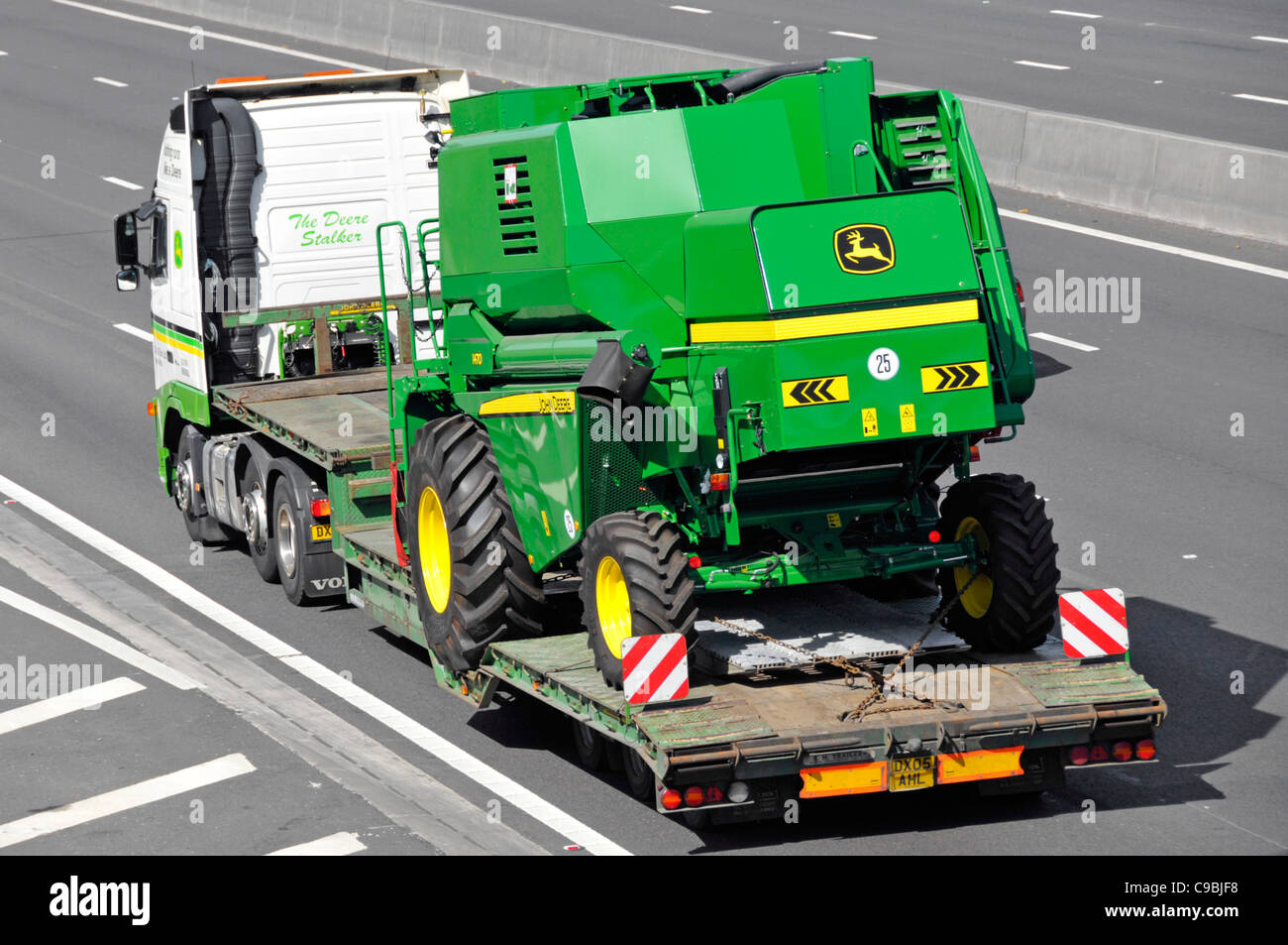Farm machinery product by John Deere hgv lorry and articulated low loader transporting a John Deere combine harvester machine motorway Essex England Stock Photo