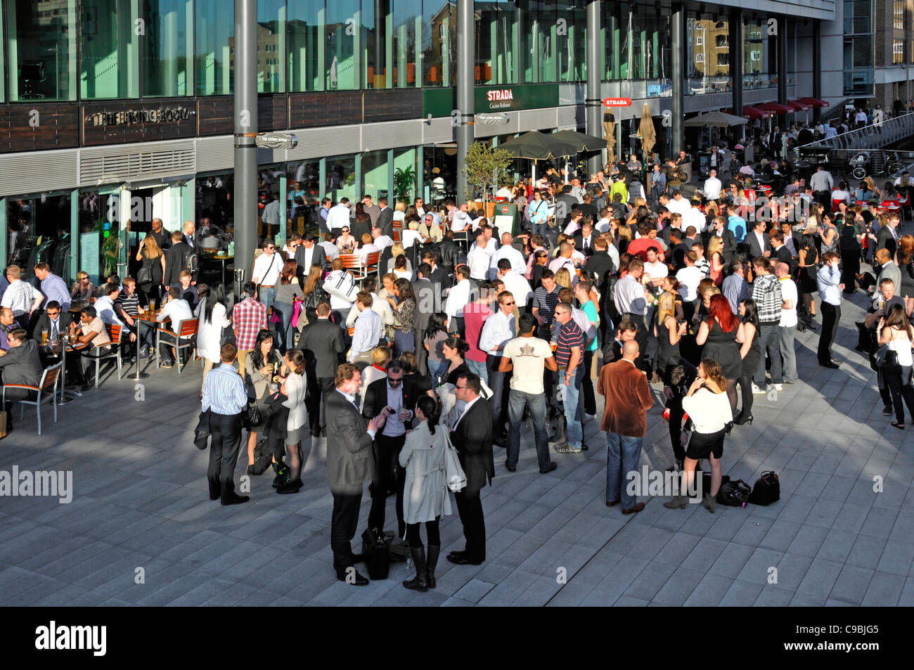 Aerial view of crowd of office workers after work lifestyle drinks group of people socialising outside busy bar business St Katharines Dock London UK Stock Photo