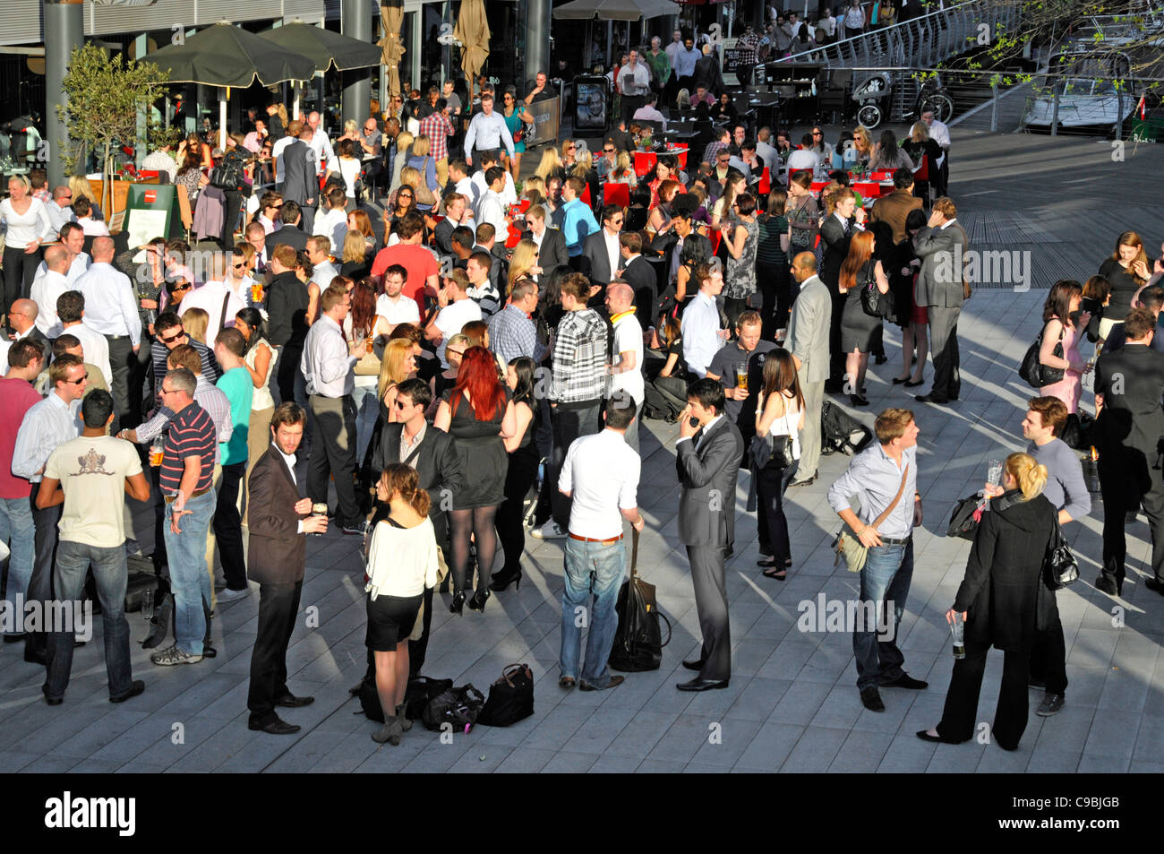 Aerial view of crowd of office workers after work lifestyle drinks group of people socialising outside bar St Katharines Dock Tower Hamlets London UK Stock Photo