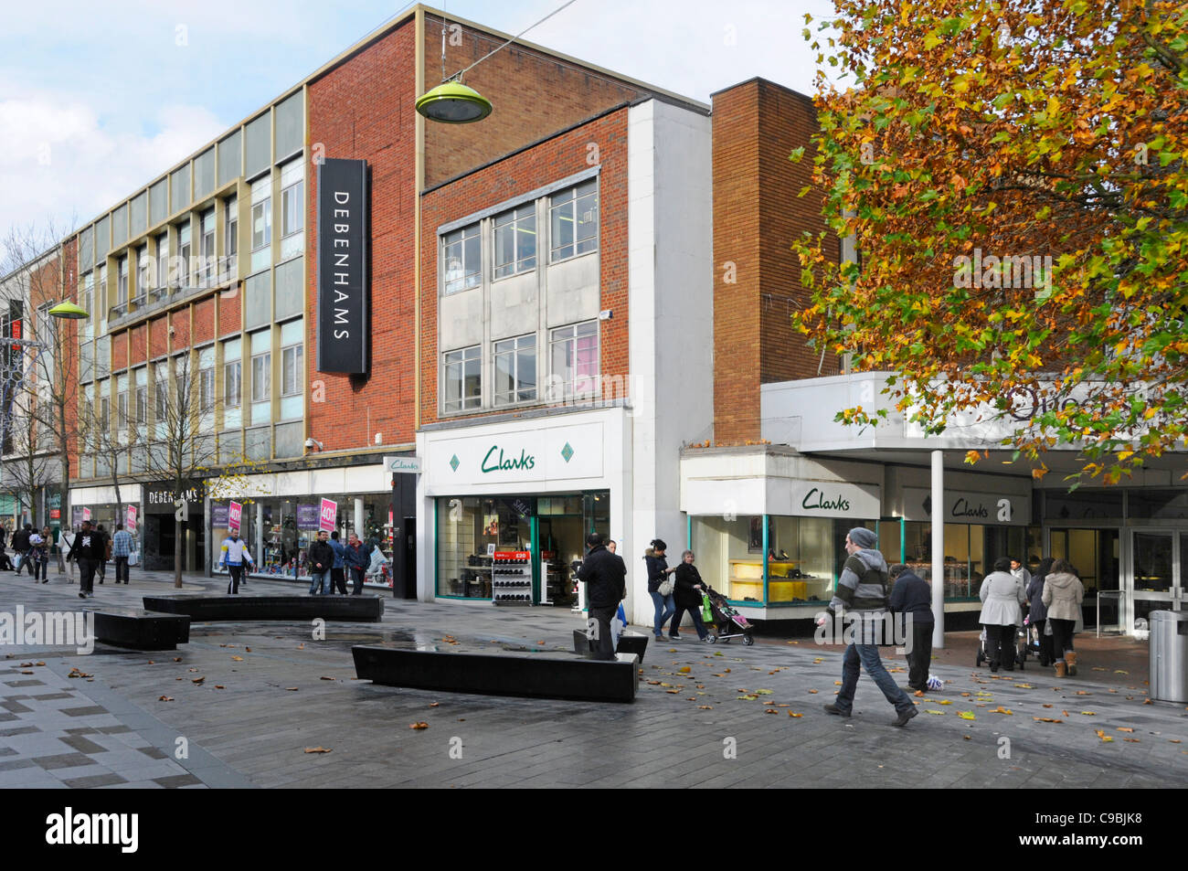 Autumn trees in town centre street scene & shopping High Street Debenhams department store & Clarks shoes shop front window in Slough Berkshire UK Stock Photo