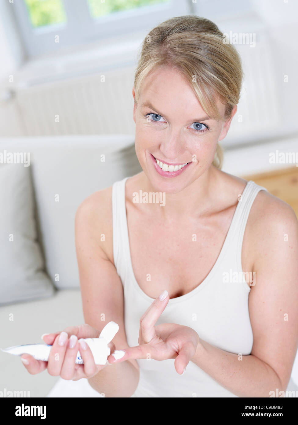 Mature woman holding cream tube, smiling, portrait Stock Photo - Alamy