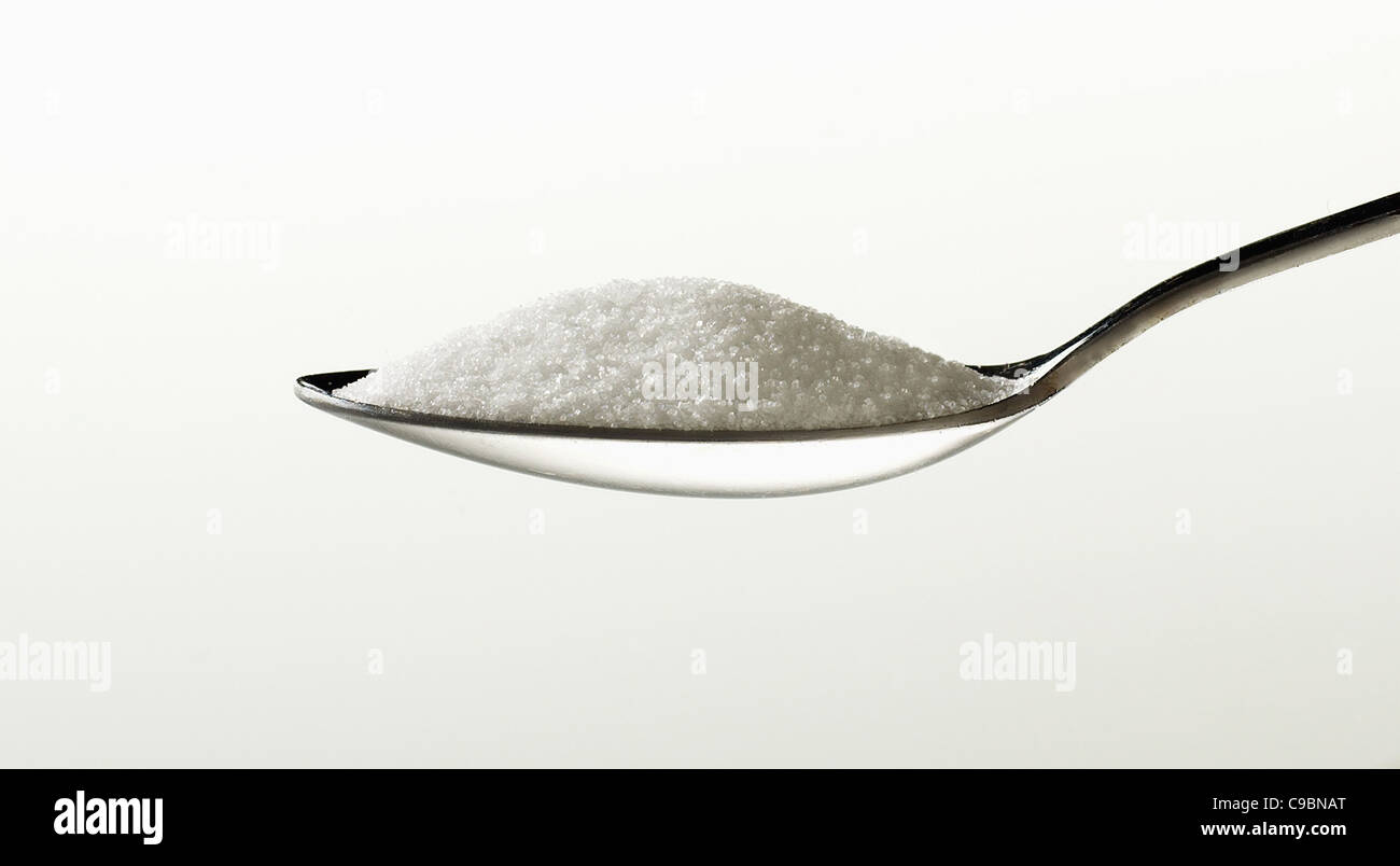 Sugar in spoon against white background Stock Photo Alamy