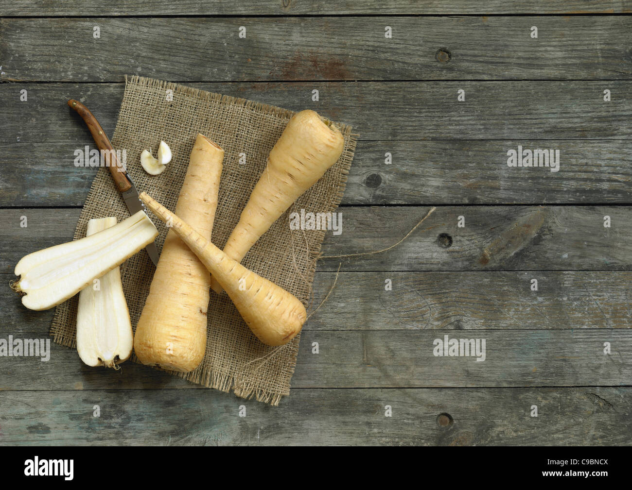 Parsnips with knife on wooden table Stock Photo