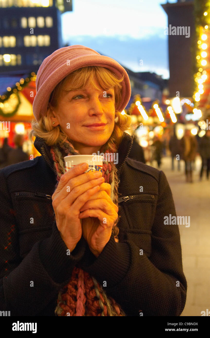 Germany, Hamburg, Mature woman holding cup and looking away Stock Photo