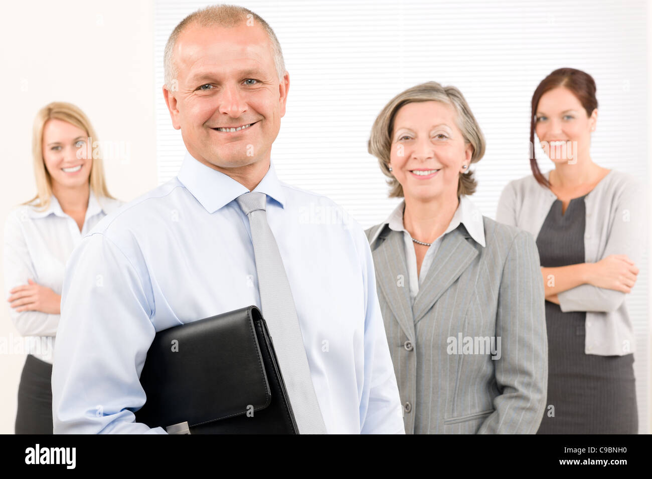 Business team mature businessman with attractive happy colleagues in office Stock Photo
