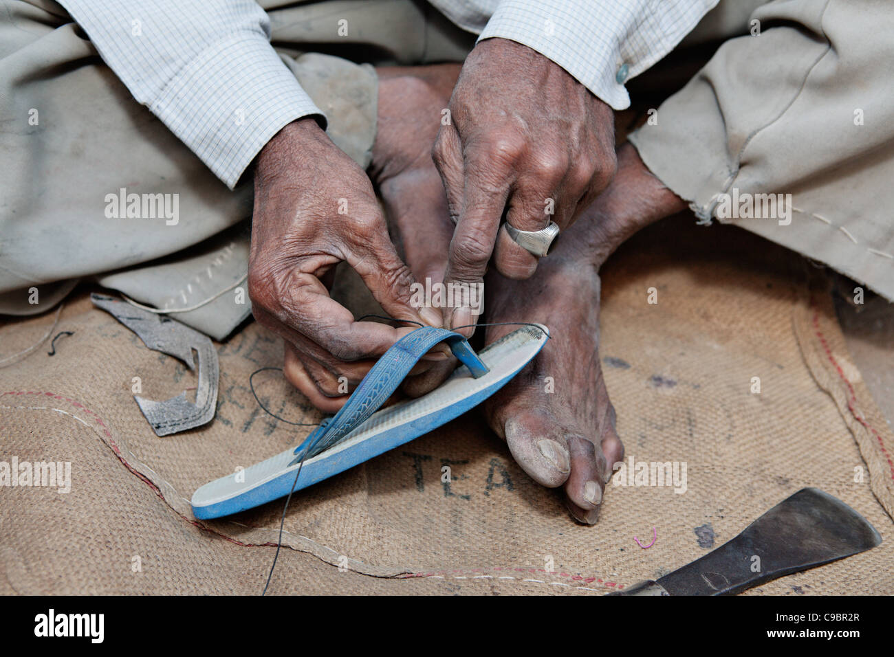 Man repairing shoes on street in village of Sarod, Gujarat state, India. Stock Photo
