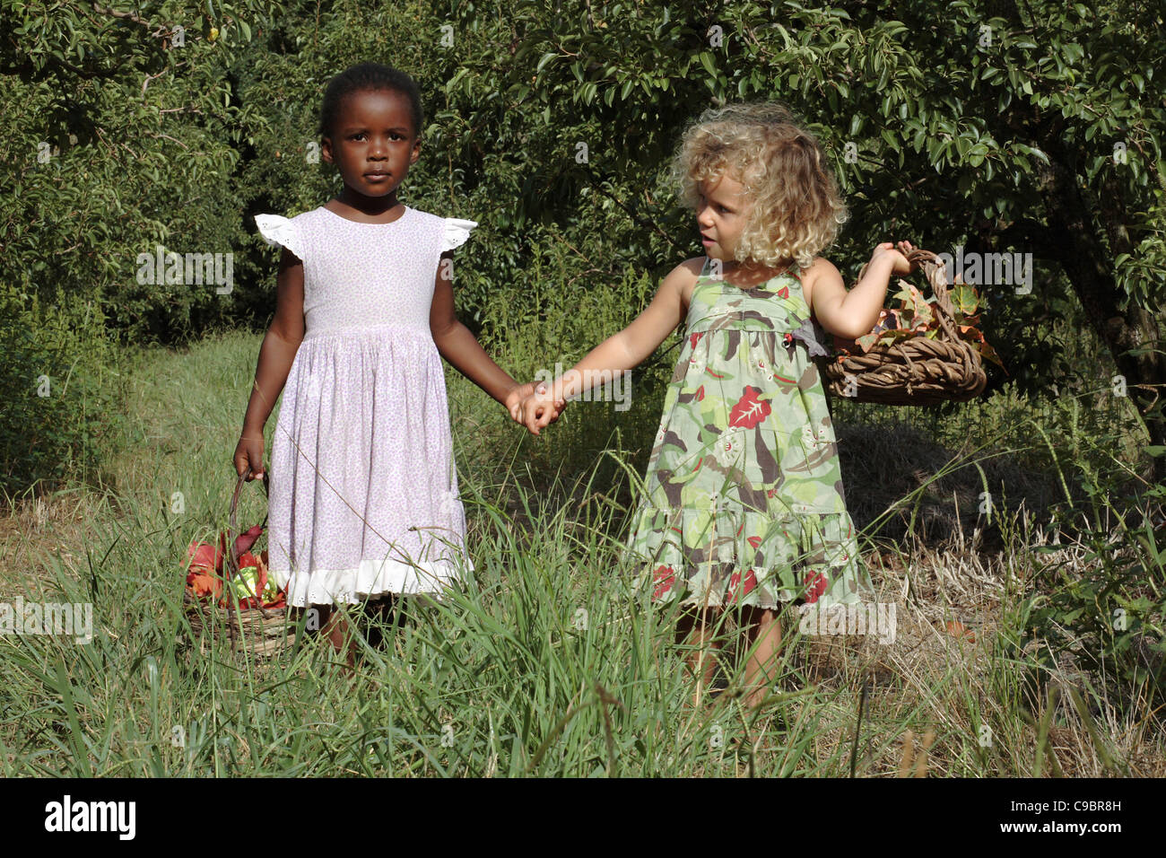 Two girls holding hands in the apple orchard, Grabouw, Cape Town