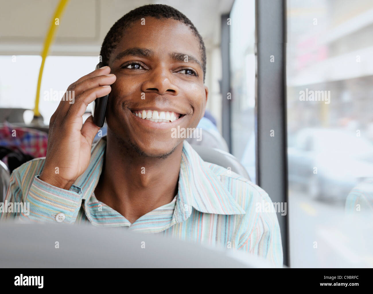 Young man sitting on bus, using mobile phone, Cape Town, Western Cape Province, South Africa Stock Photo