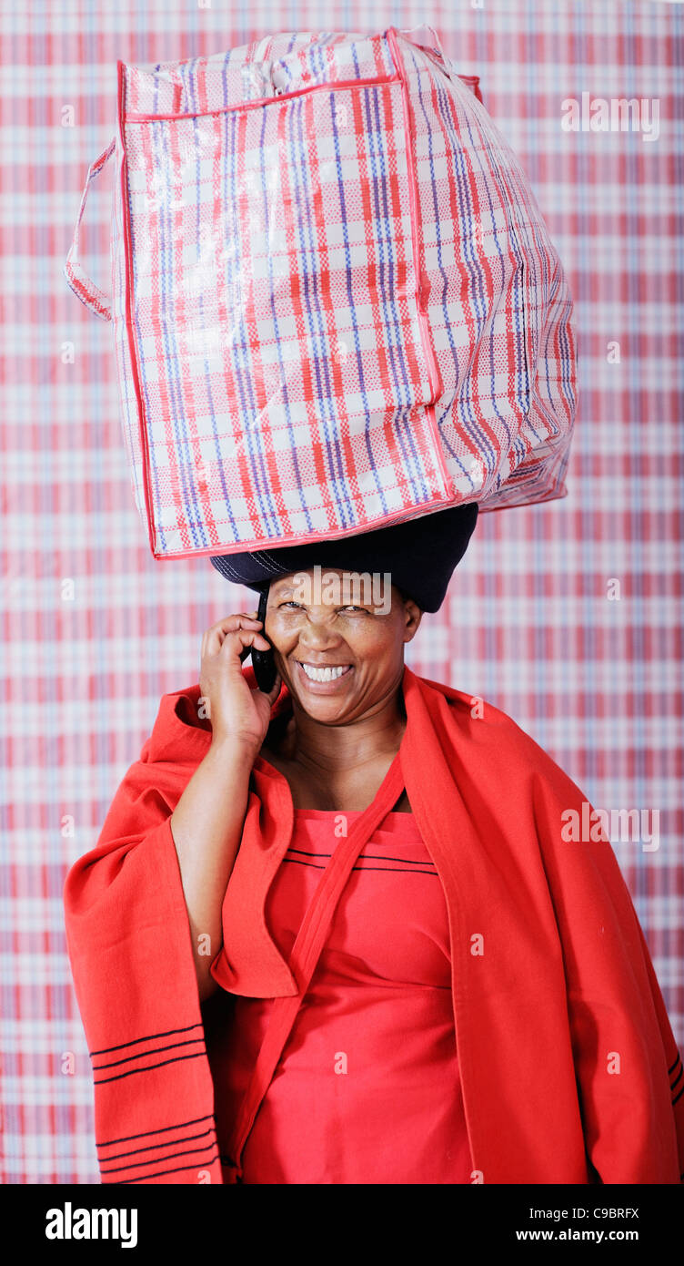 Woman in traditional outfit carrying bag on using mobile phone, Cape Town, Western Cape Province, South Africa Stock Photo