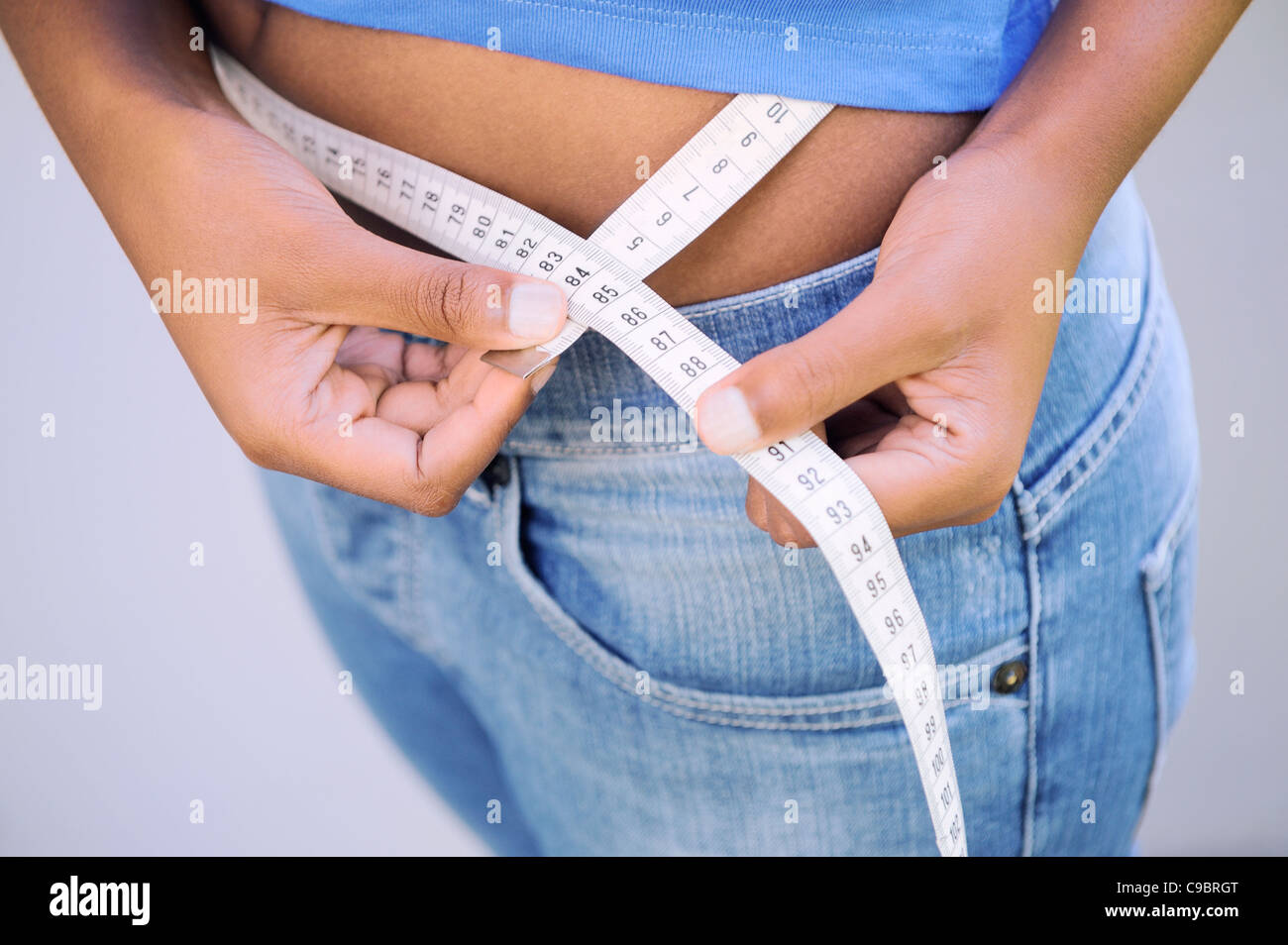 Close up of teenage girl measuring waist, Cape Town, Western Cape Province, South Africa Stock Photo