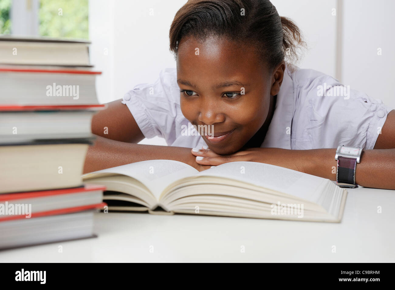Female teenage student reading, with pile of books in front of her, Cape Town, Western Cape Province, South Africa Stock Photo
