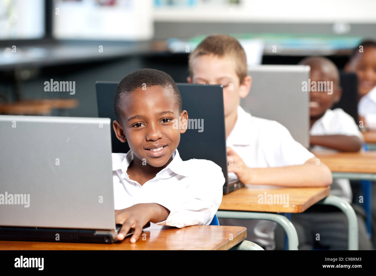 Portrait of boy working on laptop computer in classroom, Johannesburg ...