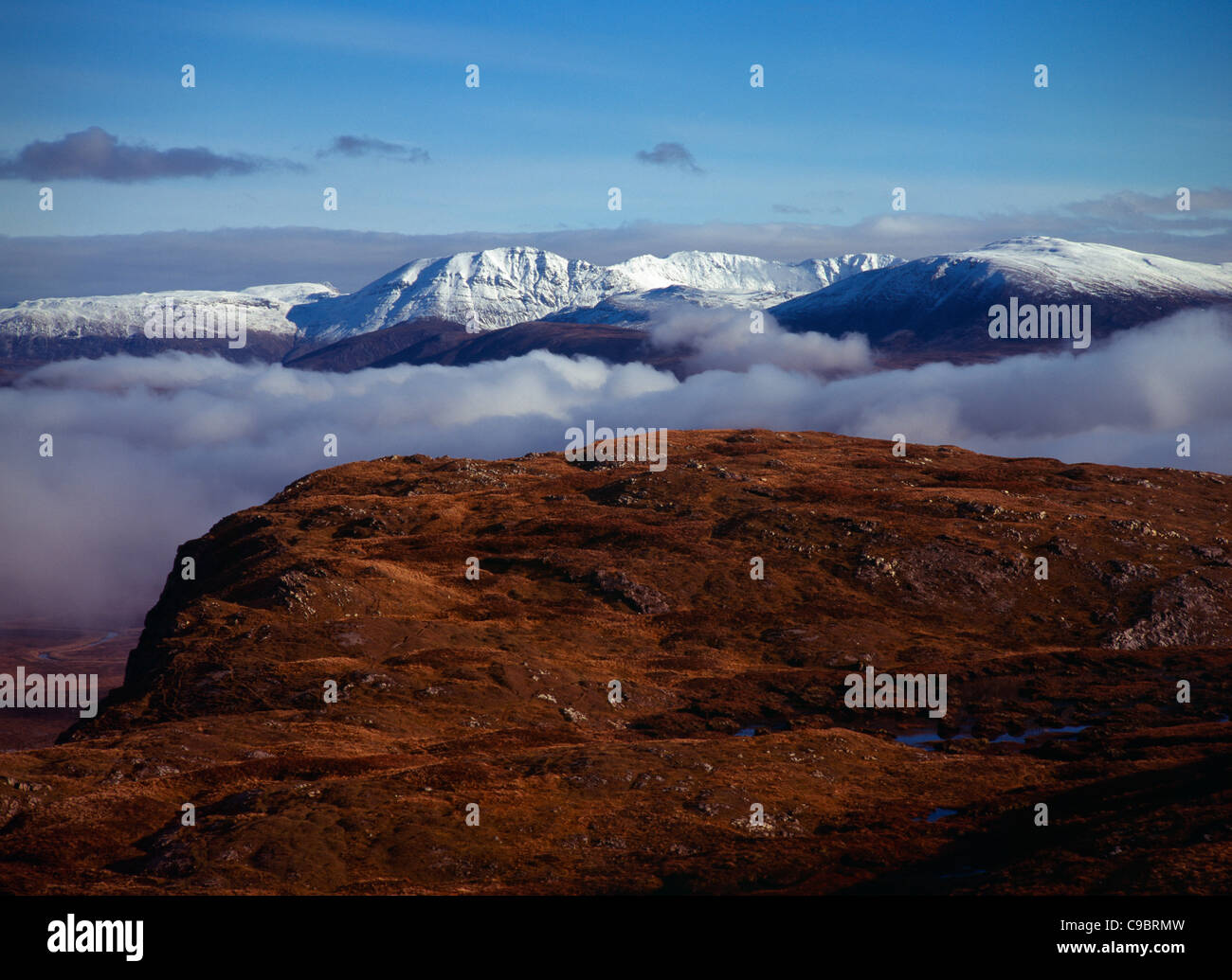 Scotland, Highlands, West, Ben More Forest and snow covered Assynt Mountains above thick white clouds Stock Photo