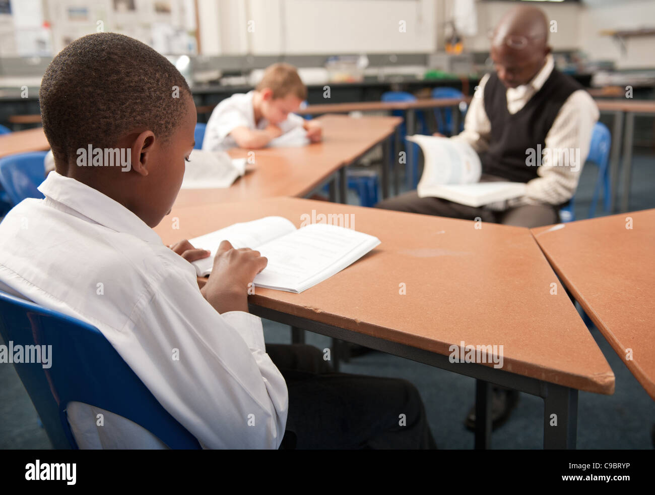Male teacher reading to boys in school classroom, Johannesburg, Gauteng Province, South Africa Stock Photo