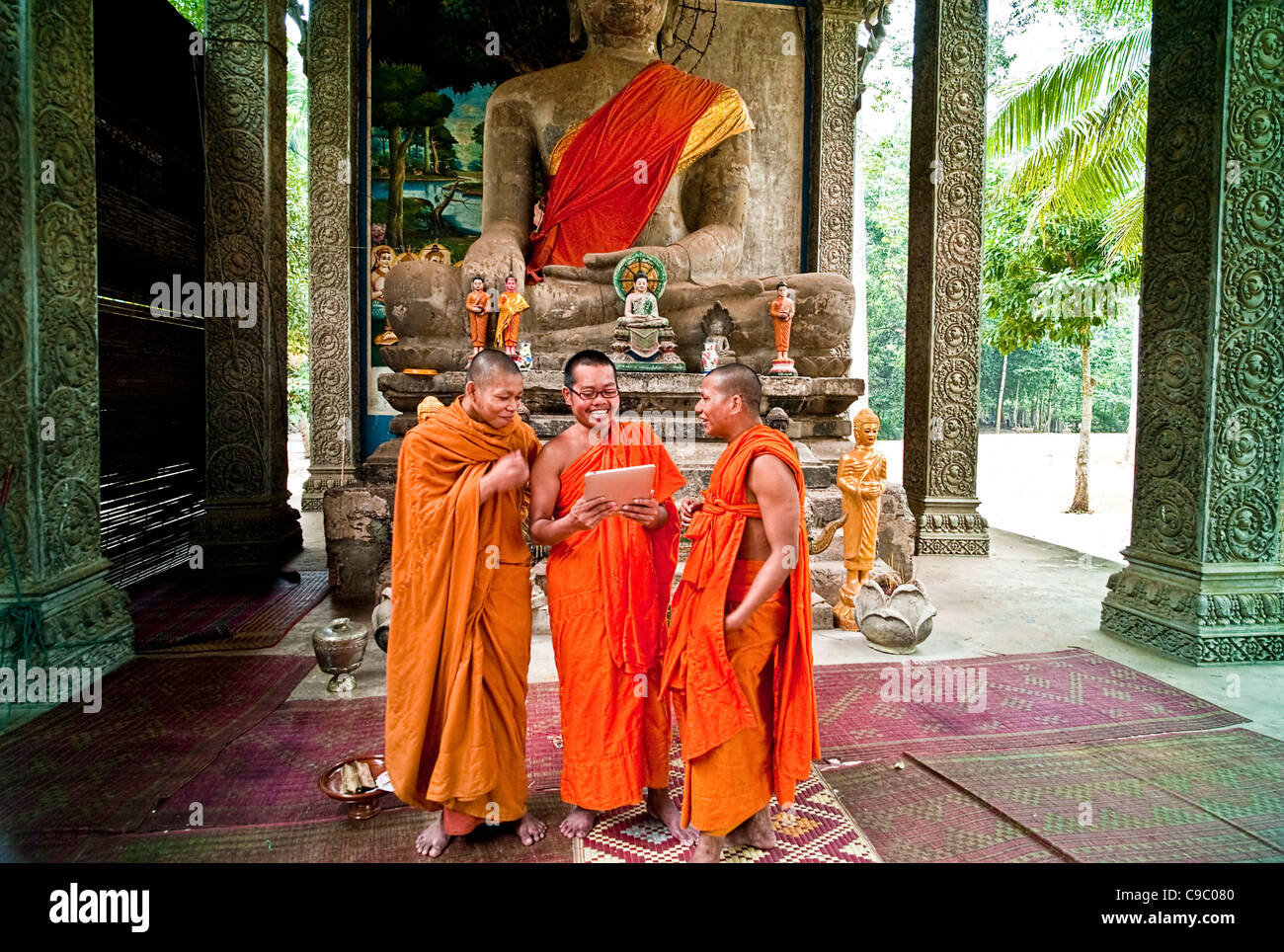 Cambodia, Siem Reap, Angkor Thom, Buddhist monks laughing at a picture on a digital reading tablet. Stock Photo