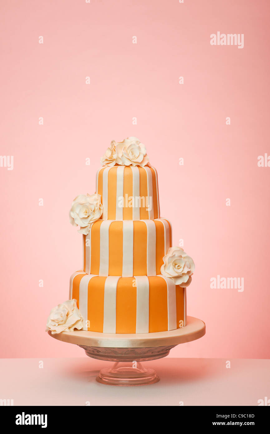 Orange striped wedding cake with peach background Stock Photo - Alamy
