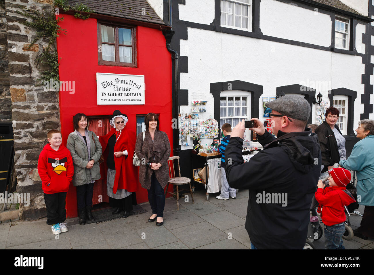 Tourists pose for a photographs outside the 'Smallest House in Great Britain', Conwy, Wales Stock Photo