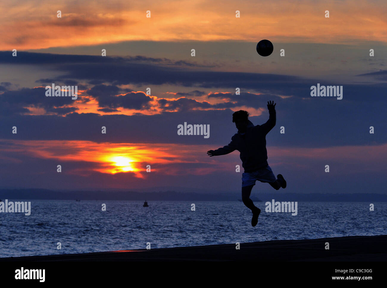 FOOTBALL AT SUNSET ON THE BEACH AT SOUTHSEA, HAMPSHIRE Stock Photo